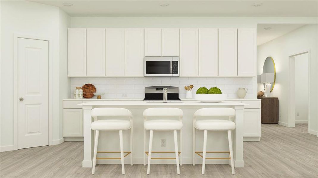 Kitchen featuring tasteful backsplash, stainless steel stove, light countertops, white microwave, and white cabinets