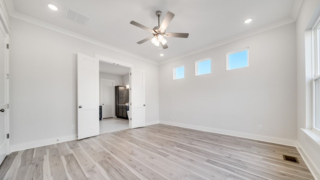 Large bedroom with hard-surface flooring, 6 windows, and door to primary bathroom