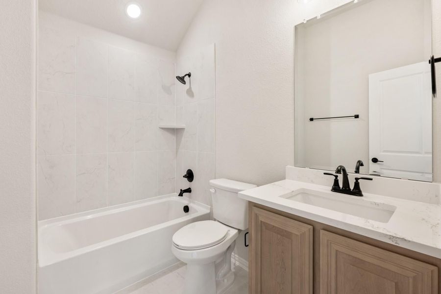 Bathroom with tub-shower combo, wood vanity with white countertop, and black fixtures