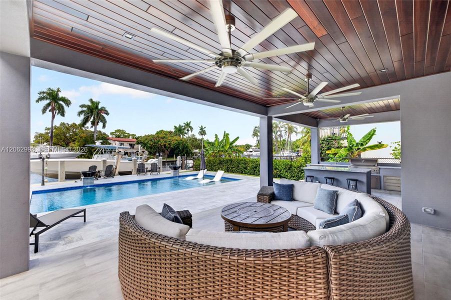 Covered patio w/ T&G ceilings, fans, fire pit seating and outdoor kitchen overlooks the gorgeous wide New River views and pool area