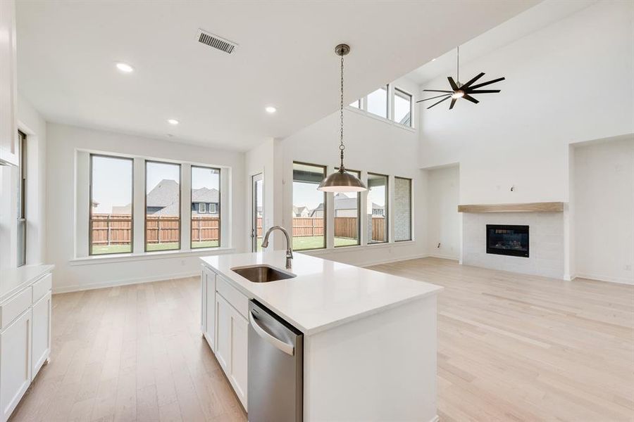 Kitchen with white cabinets, open floor plan, light wood finished floors, stainless steel dishwasher, and a towering ceiling Kitchen with white cabinets, open floor plan, light wood finished floors, stainless steel dishwasher, and a towering ceiling