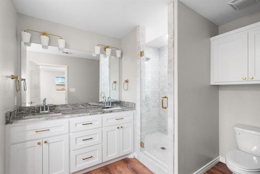 Bathroom featuring toilet, vanity, wood-type flooring, and walk in shower Bathroom featuring toilet, vanity, wood-type flooring, and walk in shower
