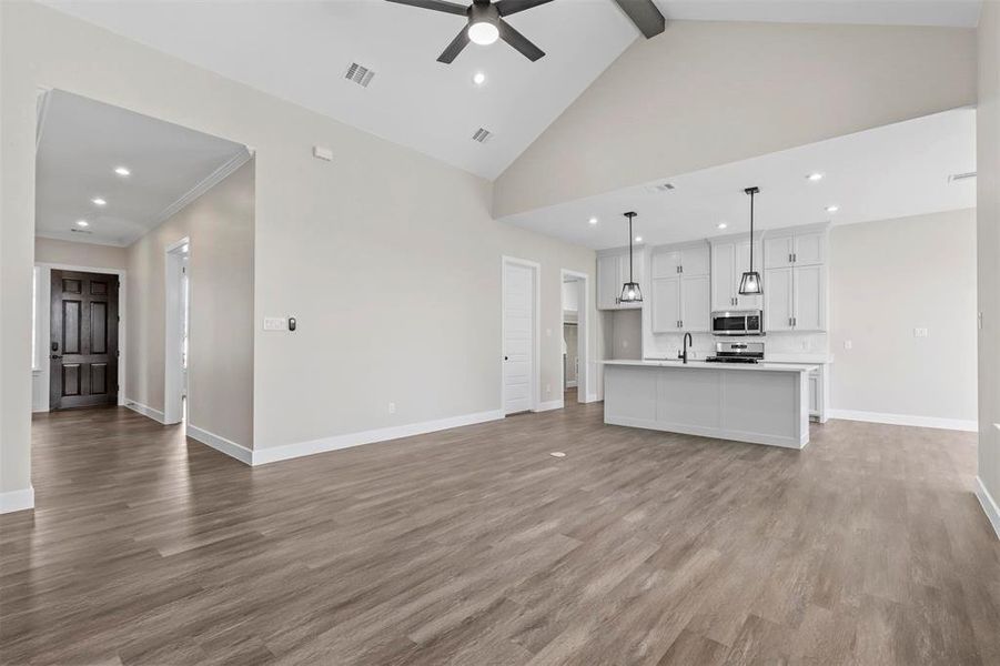 Unfurnished living room featuring light wood-type flooring, high vaulted ceiling, beamed ceiling, and ceiling fan