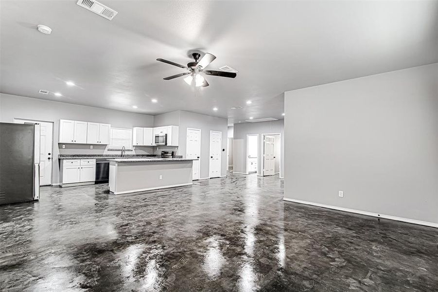 Unfurnished living room featuring ceiling fan and sink