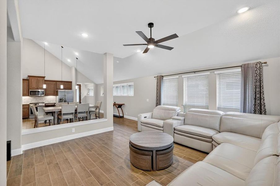 Spacious open concept living area featuring wood-finish tile flooring, a vaulted ceiling with a ceiling fan, and recessed lighting Spacious open concept living area featuring wood-finish tile flooring, a vaulted ceiling with a ceiling fan, and recessed lighting