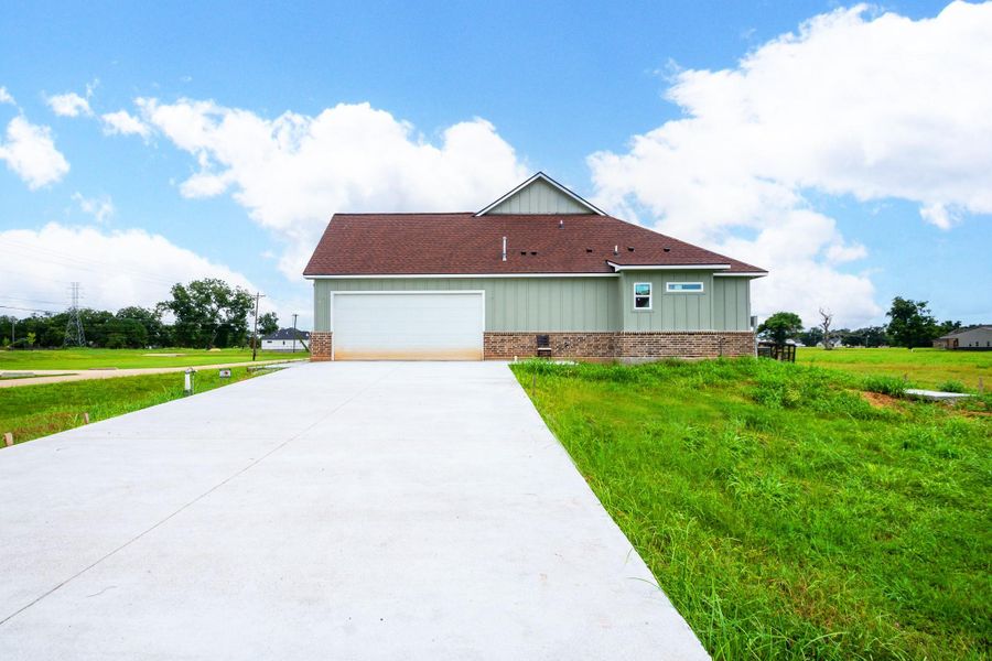 Charming home with a spacious driveway leading to a two-car garage, set against a backdrop of lush greenery and clear skies. Charming home with a spacious driveway leading to a two-car garage, set against a backdrop of lush greenery and clear skies.