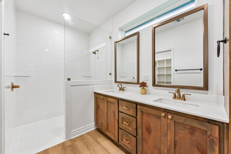 A well-appointed bathroom features a spacious glass-enclosed shower alongside dual vanities with elegant wood cabinetry. A well-appointed bathroom features a spacious glass-enclosed shower alongside dual vanities with elegant wood cabinetry.