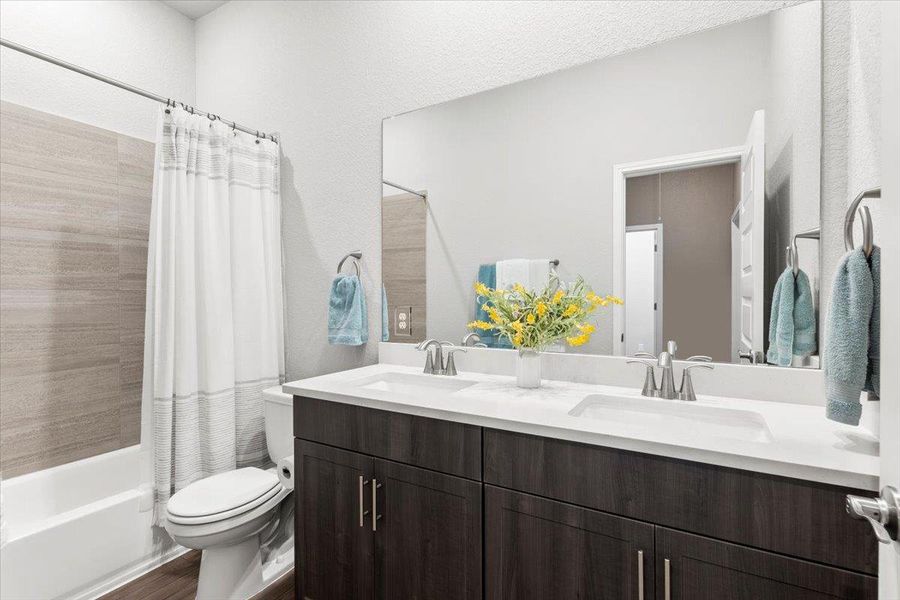 Bathroom with toilet, shower / bath combo, double vanity, and a sink