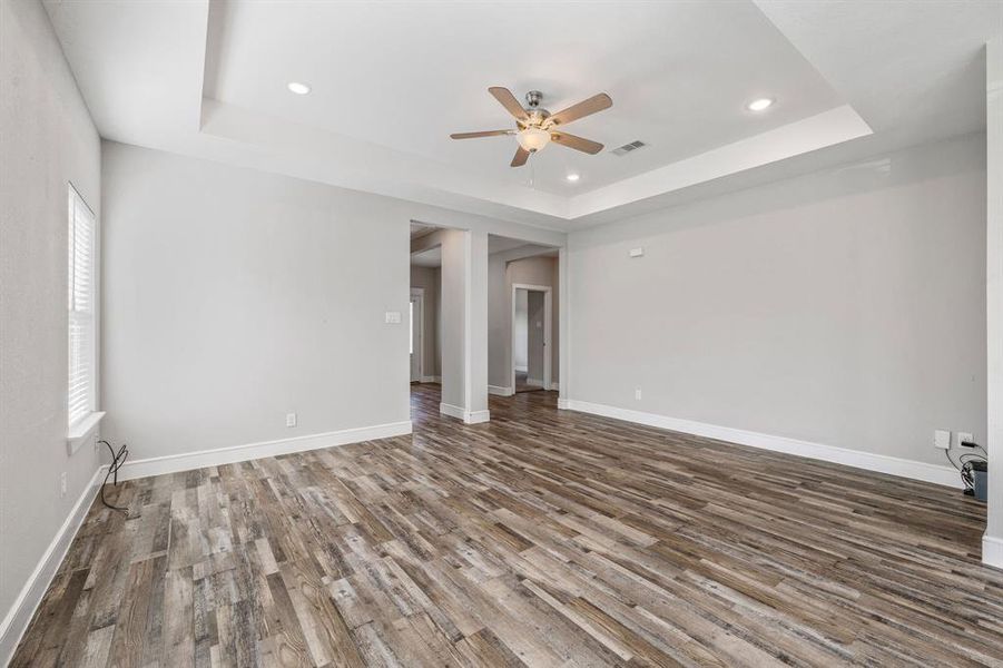 Spare room with a tray ceiling, wood finished floors, recessed lighting, and a ceiling fan Spare room with a tray ceiling, wood finished floors, recessed lighting, and a ceiling fan
