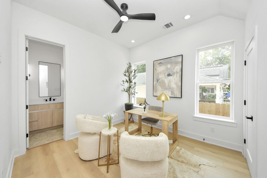Home office with a dedicated workspace, seating area, and convenient access to a full bathroom.