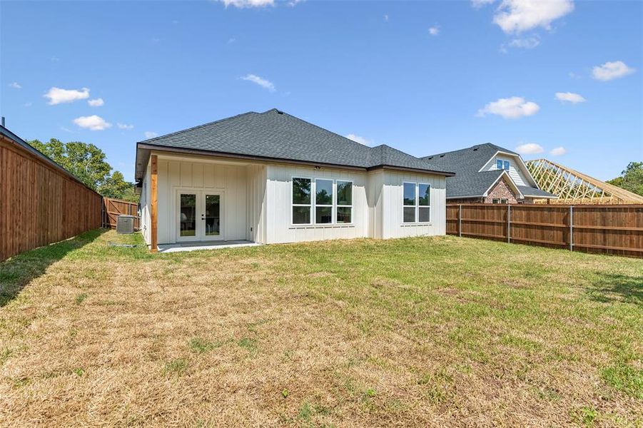 Back of property featuring central AC unit, french doors, and a lawn