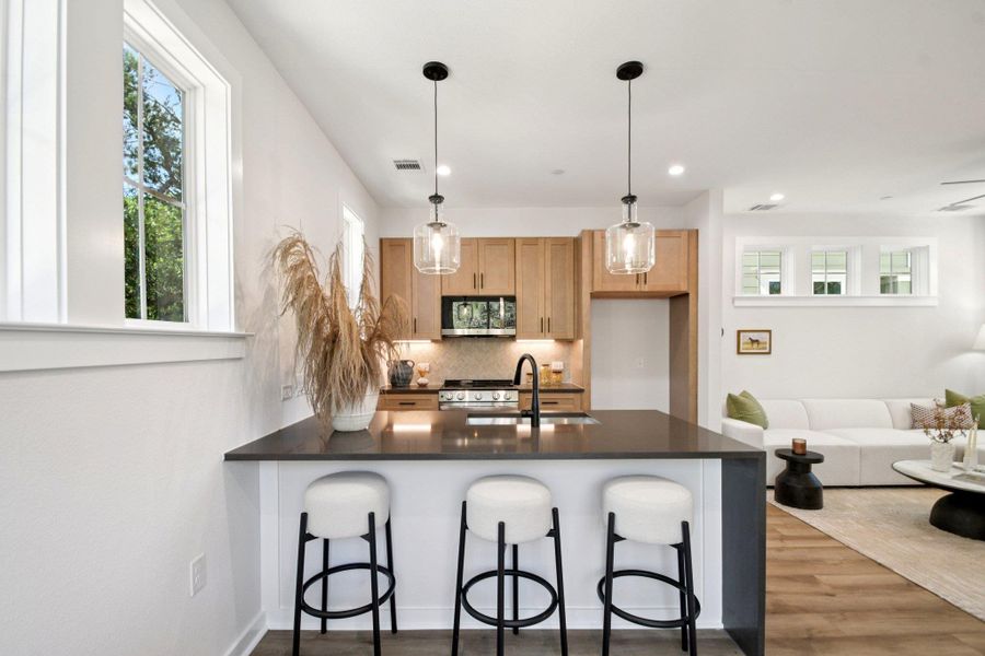 A well-appointed kitchen features a large island with seating, pendant lighting, and warm wood cabinetry. A well-appointed kitchen features a large island with seating, pendant lighting, and warm wood cabinetry.
