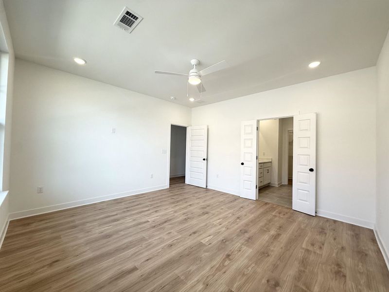 Unfurnished bedroom featuring light wood-style flooring, recessed lighting, ceiling fan, and ensuite bath