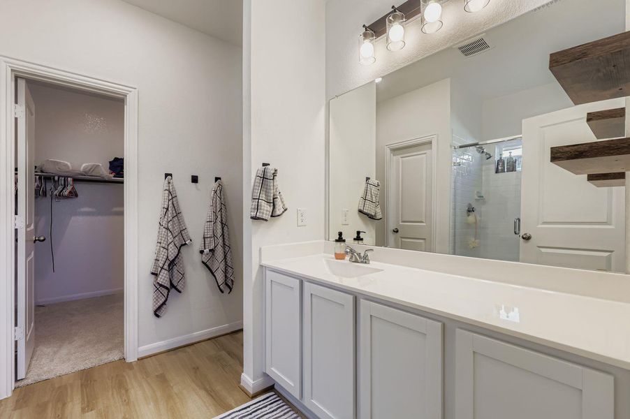 Full bathroom featuring a stall shower, a walk in closet, vanity, and light wood finished floors