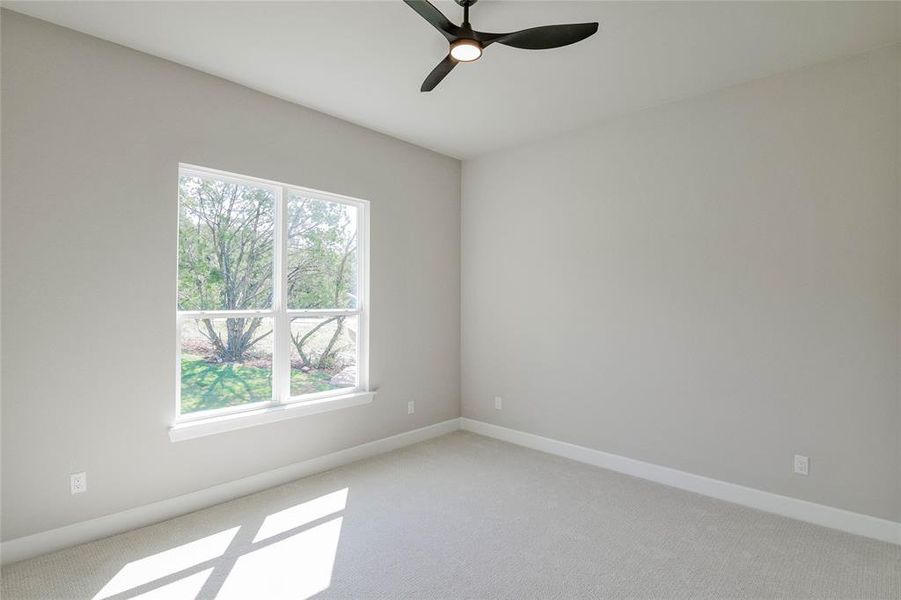 Empty room featuring light carpet and ceiling fan Empty room featuring light carpet and ceiling fan