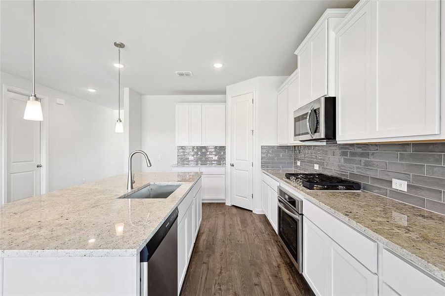 Kitchen with appliances with stainless steel finishes, white cabinets, sink, decorative backsplash, and dark hardwood / wood-style floors