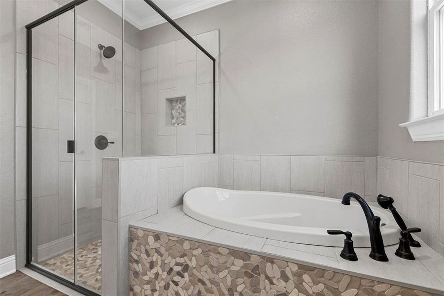 Bathroom featuring hardwood / wood-style flooring, ornamental molding, and plus walk in shower