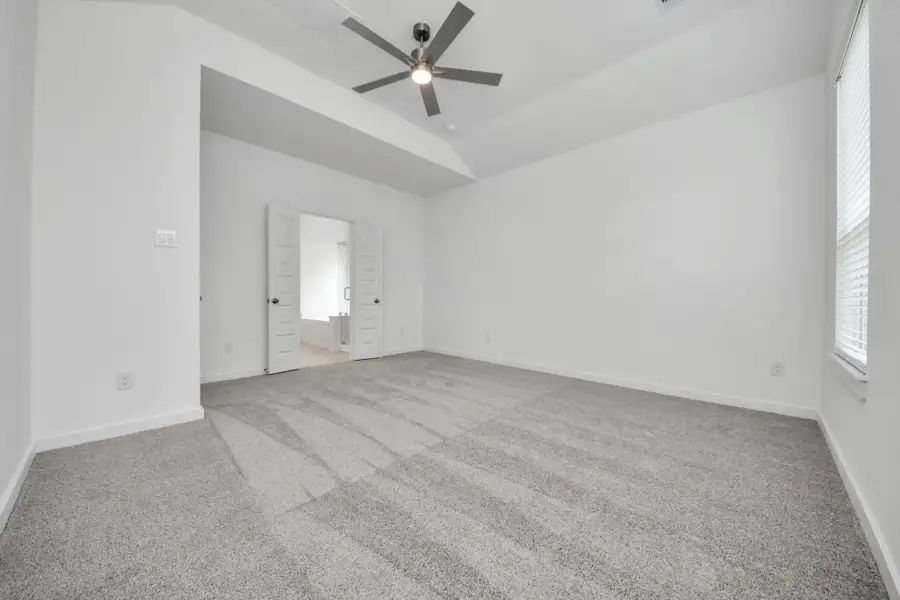 Retreat to the luxurious primary suite, your perfect escape for unwinding after a long day. Located on the first floor, this spacious room features plush carpeting, calming paint tones, high ceilings, and large windows with privacy blinds. Sample photo of completed home with similar floor plan. Actual colors and selections may vary. Retreat to the luxurious primary suite, your perfect escape for unwinding after a long day. Located on the first floor, this spacious room features plush carpeting, calming paint tones, high ceilings, and large windows with privacy blinds. Sample photo of completed home with similar floor plan. Actual colors and selections may vary.