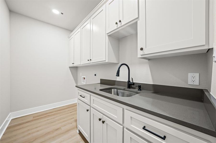 Laundry room featuring light wood-style floors, cabinet space, hookup for a washing machine, and electric dryer hookup Laundry room featuring light wood-style floors, cabinet space, hookup for a washing machine, and electric dryer hookup