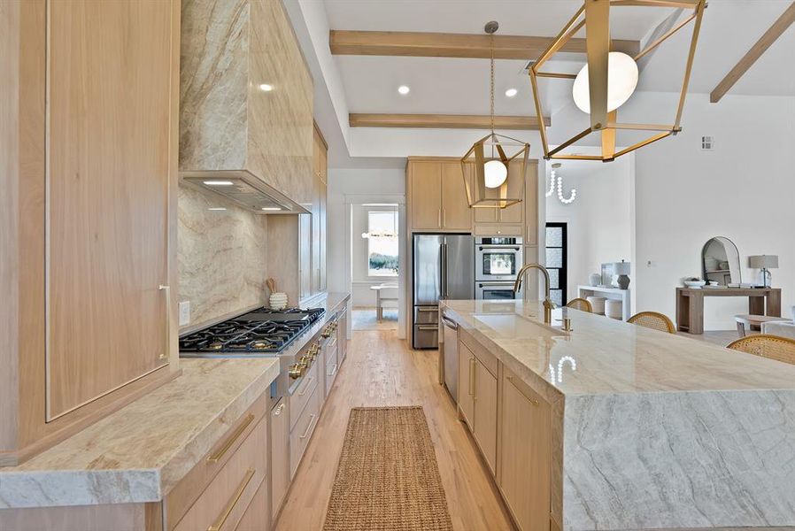Kitchen with light brown cabinetry, recessed lighting, light stone counters, light wood-style floors, and decorative light fixtures