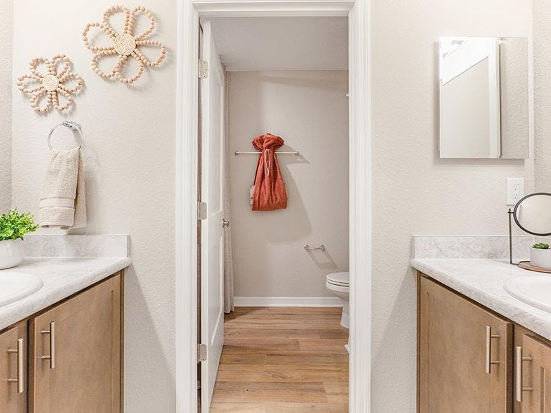 An upstairs hall bath features dual vanities and a private tub and toilet - Birch townhome by Highland Homes An upstairs hall bath features dual vanities and a private tub and toilet - Birch townhome by Highland Homes