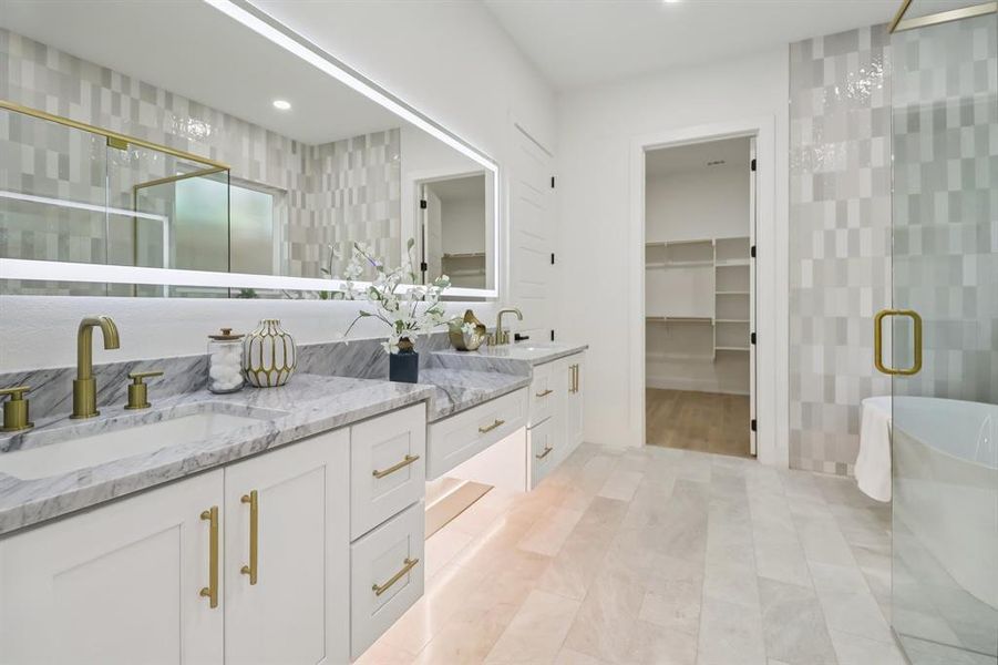 Bathroom with double vanity, a shower stall, a freestanding bath, and a spacious closet