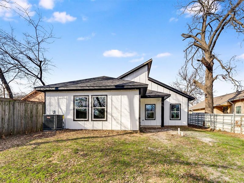 Back of house featuring a lawn and central AC