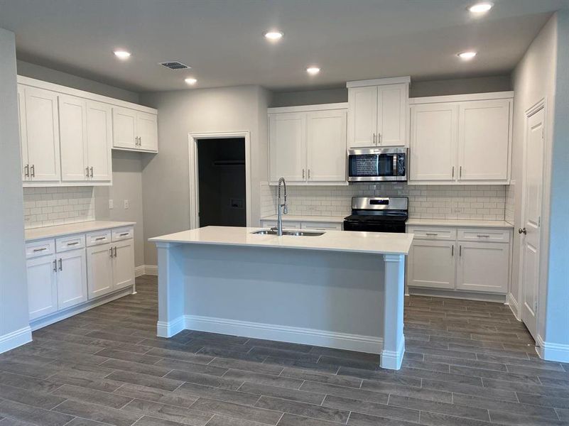 Kitchen with tasteful backsplash, sink, white cabinets, and stainless steel appliances