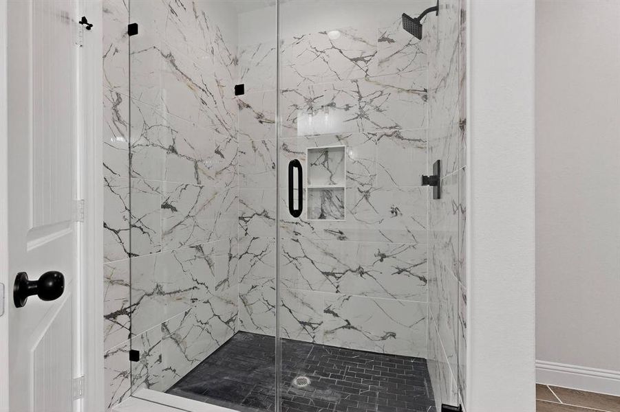 Full bathroom with a marble finish shower and baseboards Full bathroom with a marble finish shower and baseboards