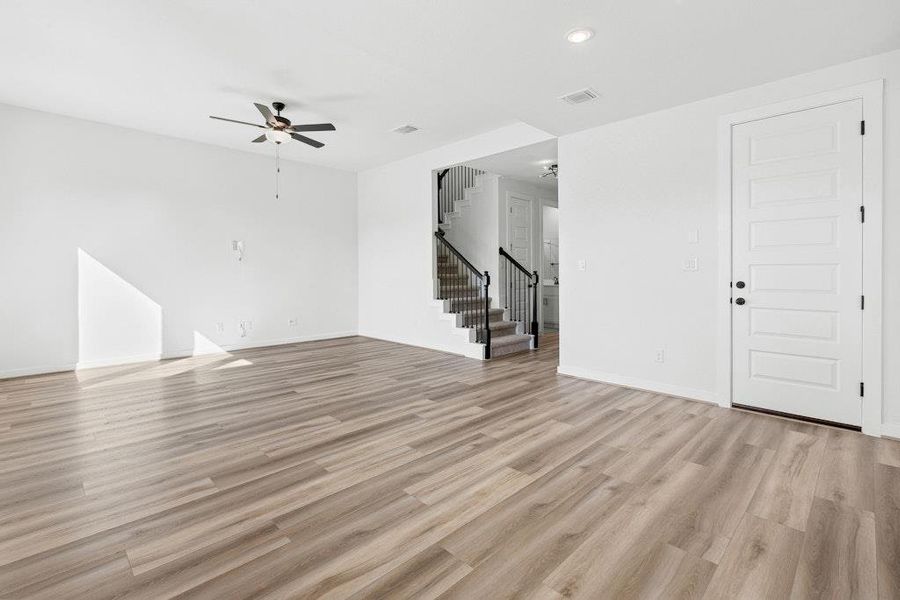 Unfurnished living room featuring light wood finished floors, stairs, recessed lighting, and ceiling fan