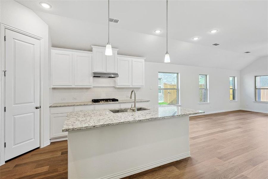 Kitchen featuring white cabinets, lofted ceiling, plenty of natural light, and sink