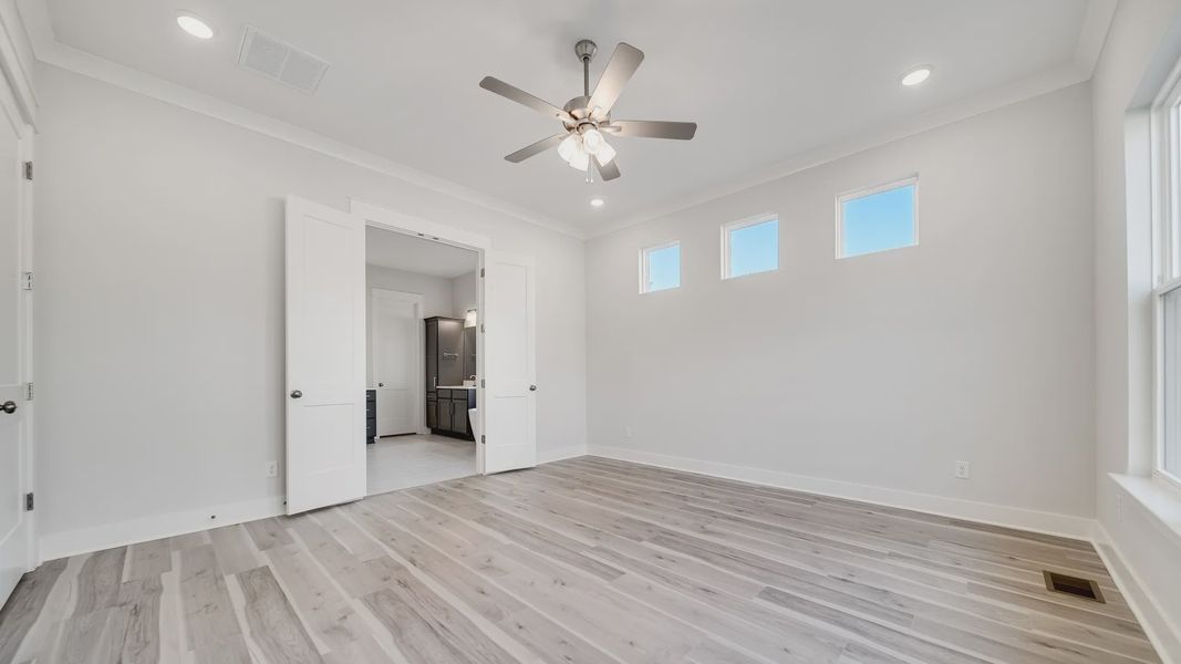Large bedroom with hard-surface flooring, 6 windows, and door to primary bathroom