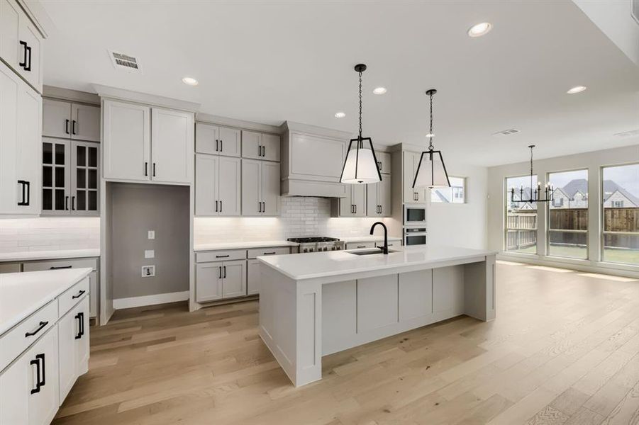 Open-concept kitchen featuring light wood-finish flooring and ample recessed lighting Open-concept kitchen featuring light wood-finish flooring and ample recessed lighting