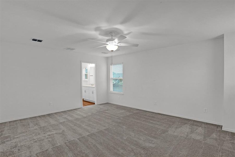 Spacious room featuring neutral carpeting, white walls, a ceiling fan with integrated lighting, and a window with horizontal blinds