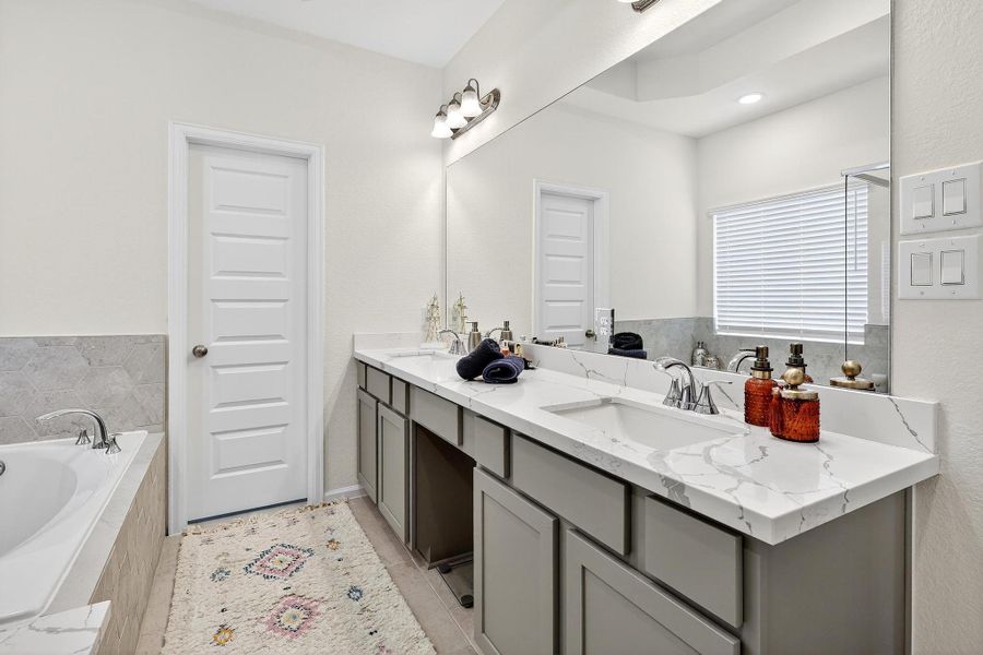 Spa-like bath featuring a soaking tub, glass-enclosed walk-in shower, and dual vanities with quartz countertops. Spa-like bath featuring a soaking tub, glass-enclosed walk-in shower, and dual vanities with quartz countertops.