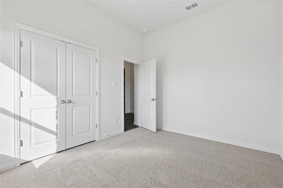 Unfurnished bedroom with light carpet and a closet