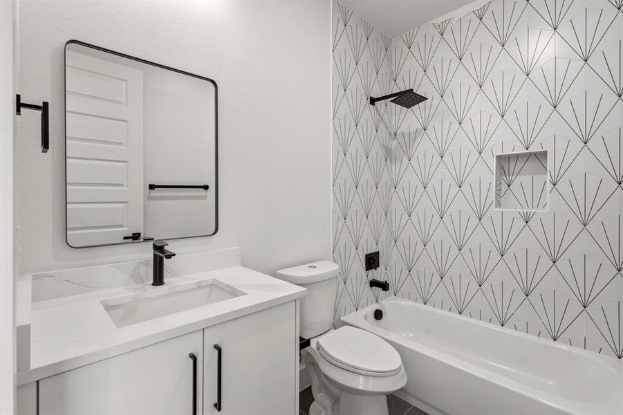Bathroom featuring a white vanity with a rectangular sink, a black framed mirror, and a bathtub with a tiled surround