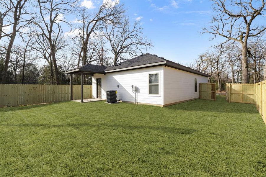 Rear view of property featuring central AC and a yard