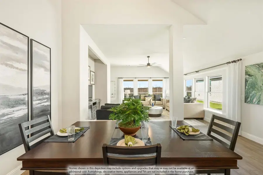 Dining area with dark wood table open to living room with ceiling fan and large windows