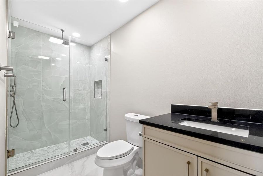 Bathroom featuring vanity, a marble finish shower, and marble finish floors Bathroom featuring vanity, a marble finish shower, and marble finish floors