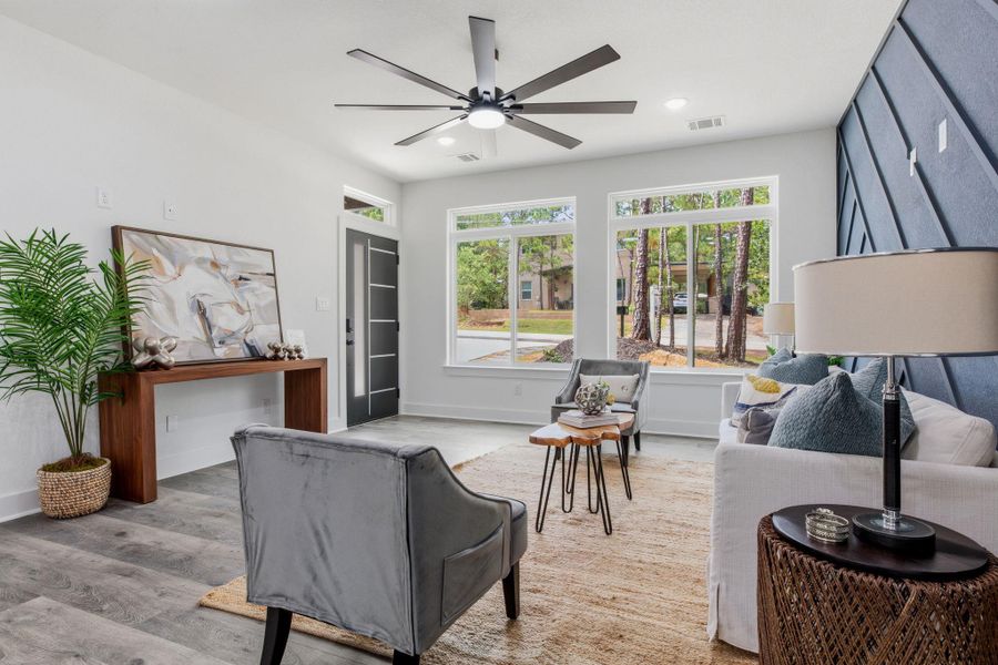 A well-lit gathering space with broad windows and elegant wooden flooring, perfect for comfortable living.