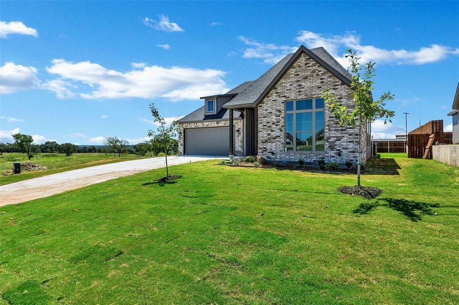 View of front of property featuring driveway, brick siding, and an attached garage