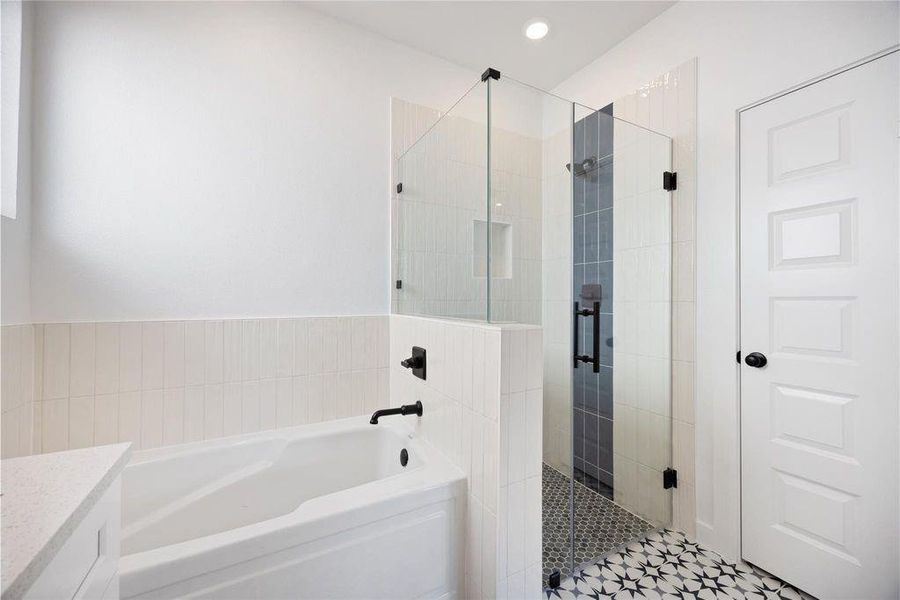 This bathroom features a modern design with a glass-enclosed shower, stylish black fixtures, and a separate bathtub. The patterned tile floor adds a touch of elegance and character to the space. This bathroom features a modern design with a glass-enclosed shower, stylish black fixtures, and a separate bathtub. The patterned tile floor adds a touch of elegance and character to the space.