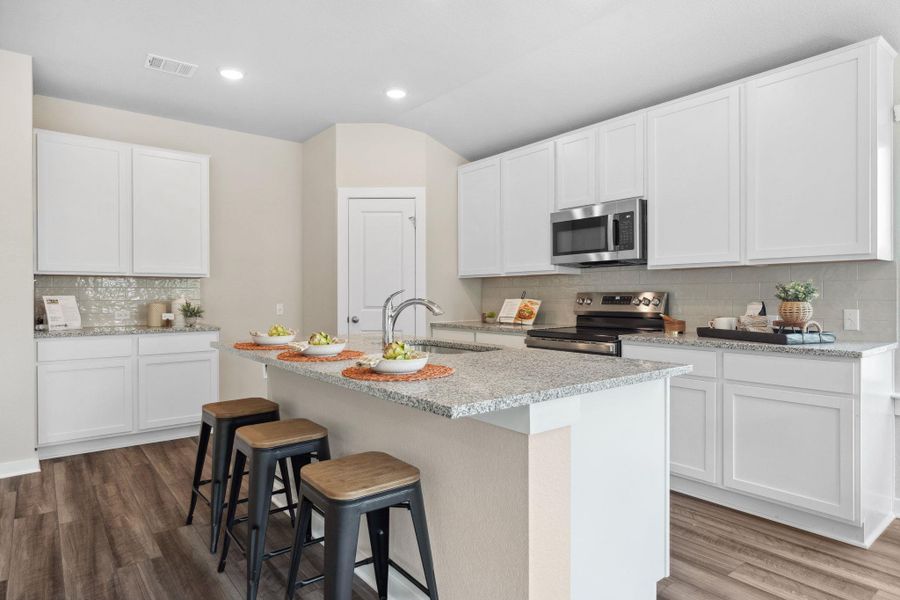 Kitchen with decorative backsplash, a breakfast bar area, stainless steel appliances, light stone countertops, and dark wood-style floors Kitchen with decorative backsplash, a breakfast bar area, stainless steel appliances, light stone countertops, and dark wood-style floors