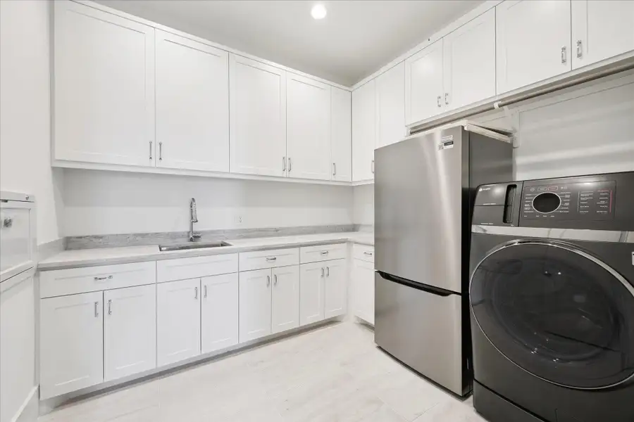 Nicely sized utility room with sink and ample counter space conveniently located on the second floor adjacent to the primary and secondary bedrooms. All-in-one washer and dryer and refrigerator/freezer combo convey with the sale of the home. Nicely sized utility room with sink and ample counter space conveniently located on the second floor adjacent to the primary and secondary bedrooms. All-in-one washer and dryer and refrigerator/freezer combo convey with the sale of the home.