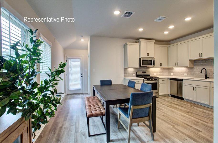 Kitchen with light wood-type flooring, stainless steel appliances, white cabinetry, and sink