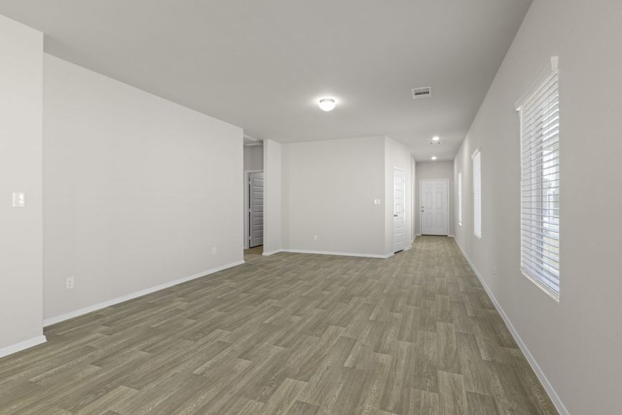 Image of a living room with beige walls, light brown wood-look flooring, and windows with blinds Image of a living room with beige walls, light brown wood-look flooring, and windows with blinds
