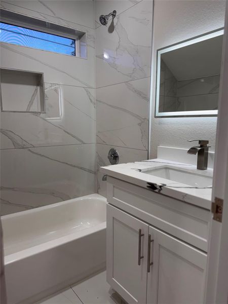 Elegant bathroom featuring marble-patterned tiles, a sleek vanity with a modern faucet, and a backlit mirror. Elegant bathroom featuring marble-patterned tiles, a sleek vanity with a modern faucet, and a backlit mirror.