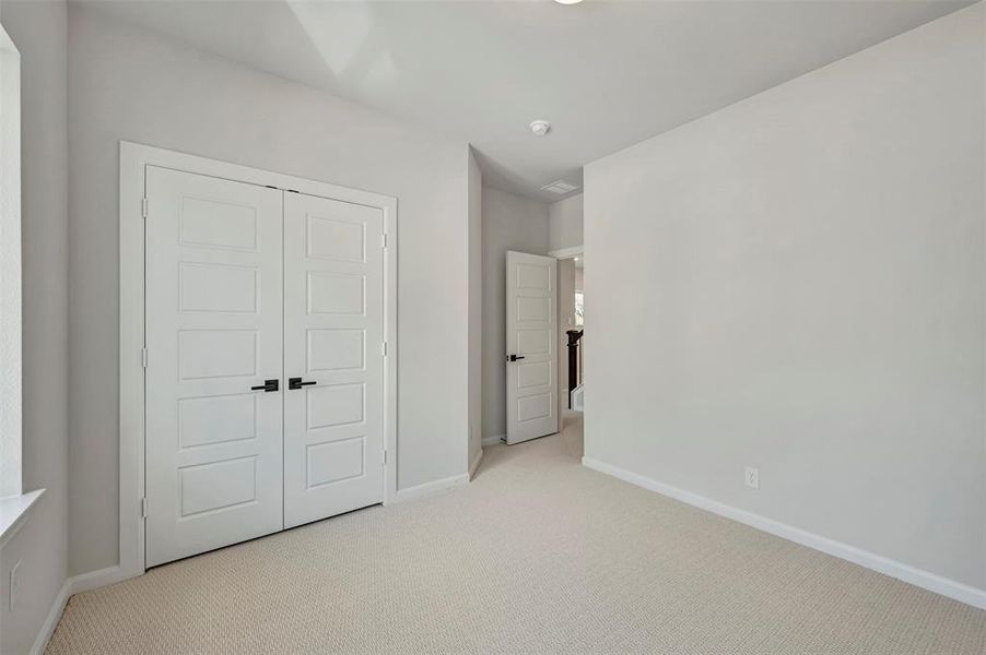 Unfurnished bedroom with light carpet and a closet Unfurnished bedroom with light carpet and a closet