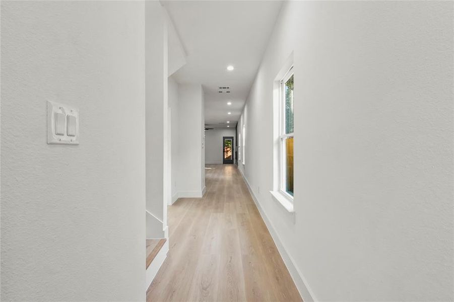 Hall with light wood-style floors and recessed lighting